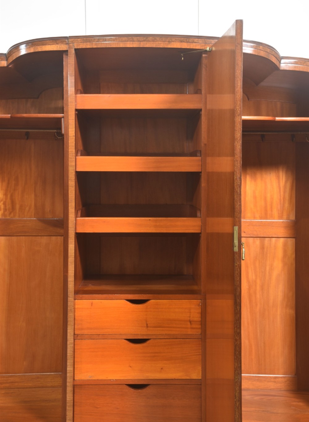 An Art Deco burr walnut breakfront wardrobe with curved side doors, a raised central door, and short carved feet. View V