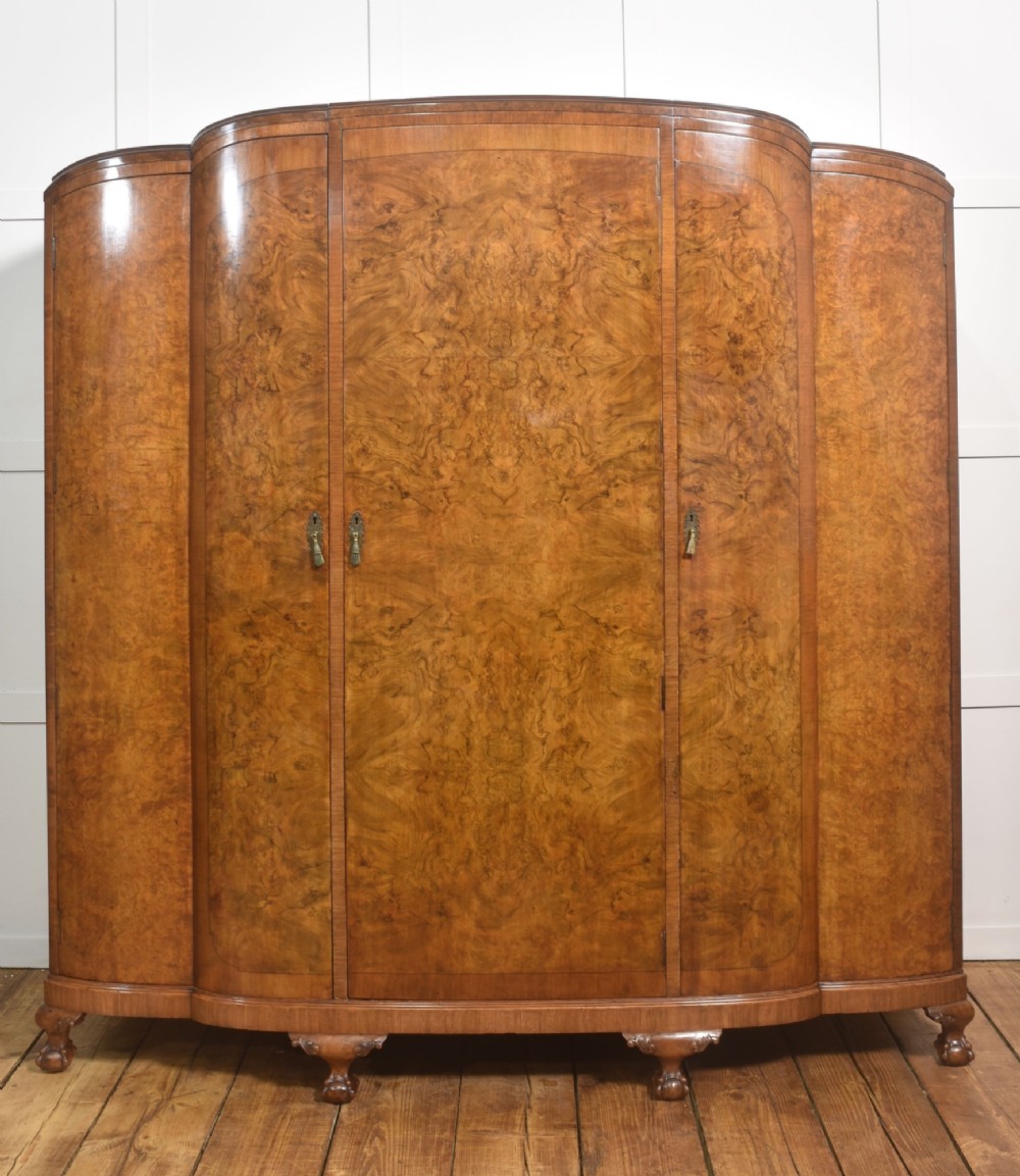 An Art Deco burr walnut breakfront wardrobe with curved side doors, a raised central door, and short carved feet. View VI