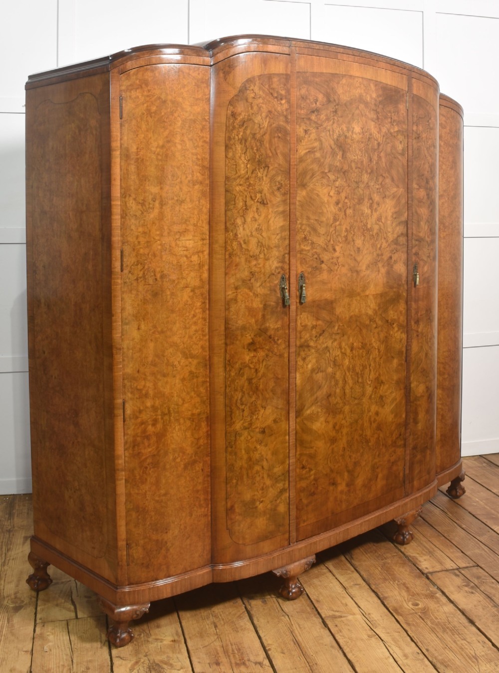 An Art Deco burr walnut breakfront wardrobe with curved side doors, a raised central door, and short carved feet. View VII