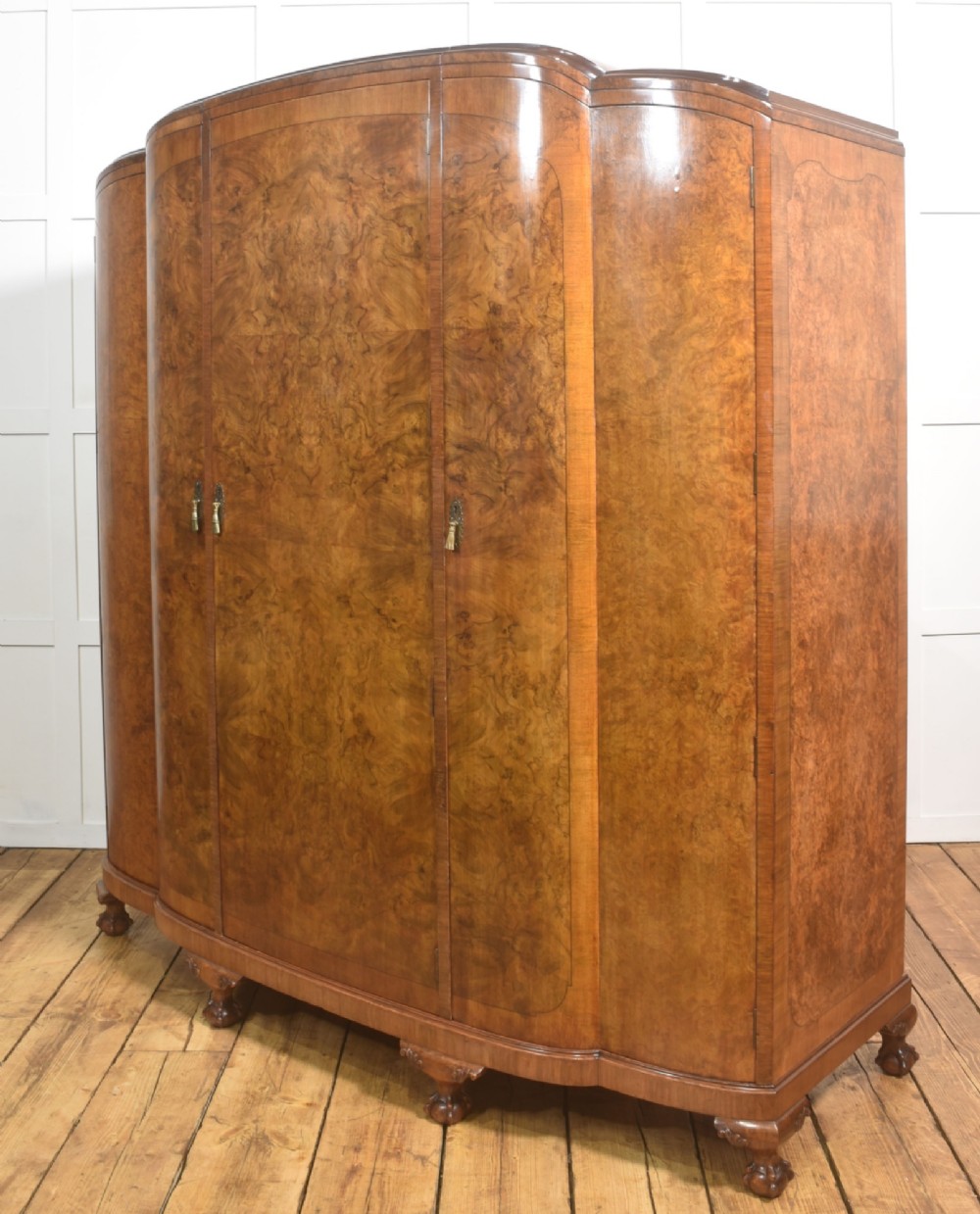 An Art Deco burr walnut breakfront wardrobe with curved side doors, a raised central door, and short carved feet. View XI
