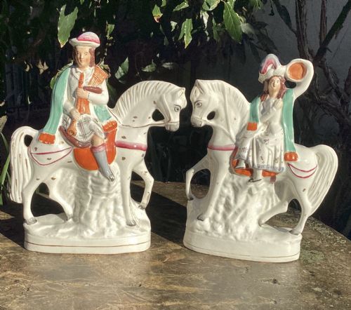 fig 1. A pair of Victorian Staffordshire white earthenware equestrian figures depicting male and female musicians seated on horses with hand-painted green, orange, and gilt accents.