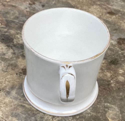 fig 1. An antique white porcelain mug decorated with hand-painted children playing and finished with gold gilt rim borders.