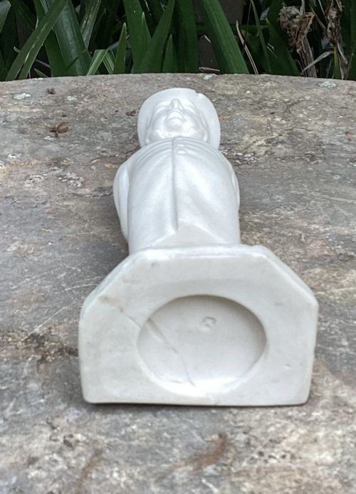 fig 1. An off-white Victorian parian porcelain figurine of a gentleman wearing a top hat and buttoned frock coat standing on a cobblestone base.