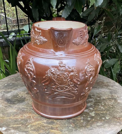 fig 1. A large Victorian brown glazed stoneware jug featuring a relief-moulded profile portrait of Queen Victoria within an ornate cartouche.