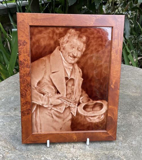 fig 1. A pair of framed, warm brown glaze ceramic tiles depicting musician figures in sepia relief.
