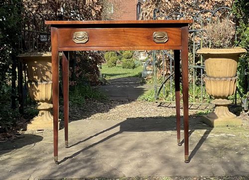 fig 1. A Georgian mahogany bow-front side table featuring a single drawer with brass handles and slender tapered legs on brass castors.