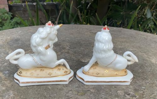 fig 1. A pair of Victorian Staffordshire white glazed ceramic figures depicting a recumbent royal lion and unicorn with gilded detailing on moulded bases.