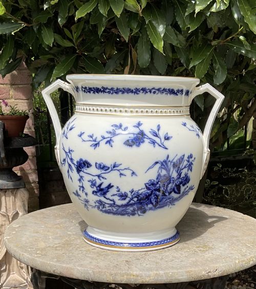 fig 1. A white earthenware urn-shaped vase featuring blue transfer-printed floral, bird, and butterfly patterns with gilded accents and two side handles.