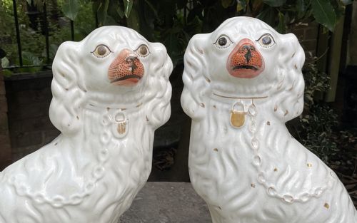 fig 1. A pair of seated Victorian white earthenware Staffordshire spaniel figurines decorated with gilded chains and painted muzzles.