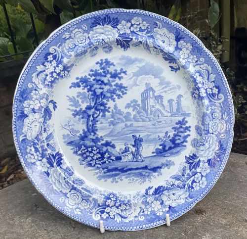 fig 1. A set of six circular Georgian blue and white transferware earthenware plates decorated with pastoral scenes, classical ruins, and intricate floral borders.