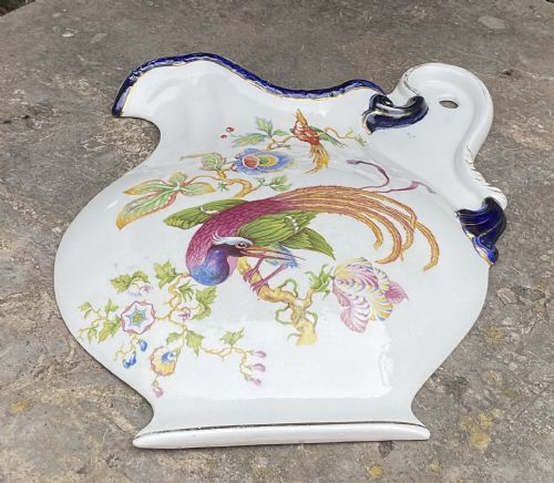 fig 1. A flat Victorian earthenware plaque shaped like a jug with a painted exotic bird on a floral branch, cobalt blue scroll rim, and gilded accents.