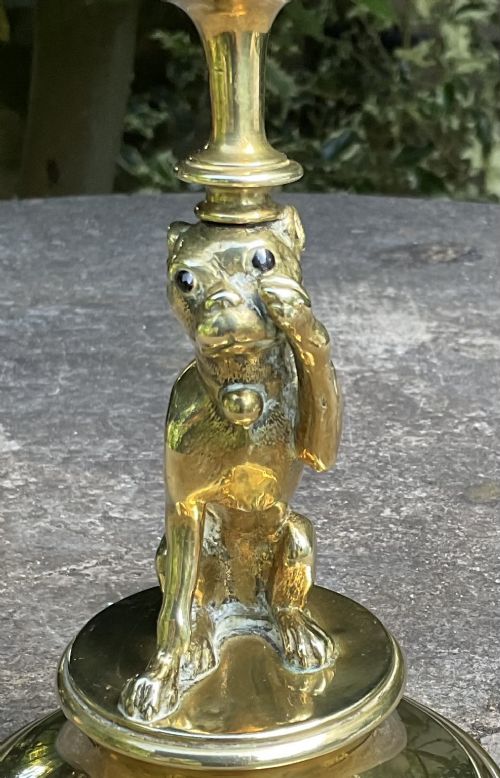 A Victorian cast brass candlestick featuring a sculpted sitting pug dog forming the lower stem above a round stepped base. View II