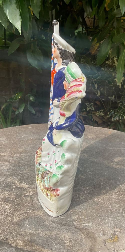 fig 1. A Victorian Staffordshire earthenware flatback figure group depicting a sailor holding a flag alongside a female figure holding a sheaf of corn.