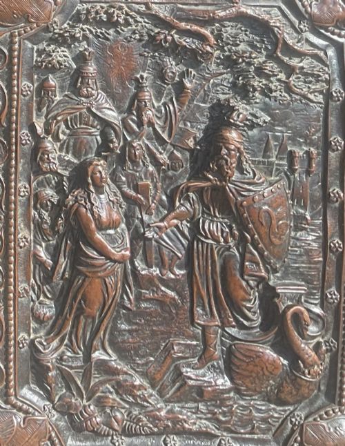 fig 1. An antique brown leather desk blotter featuring a central embossed copper relief panel depicting a scene from Wagners opera Lohengrin with a knight and swan.