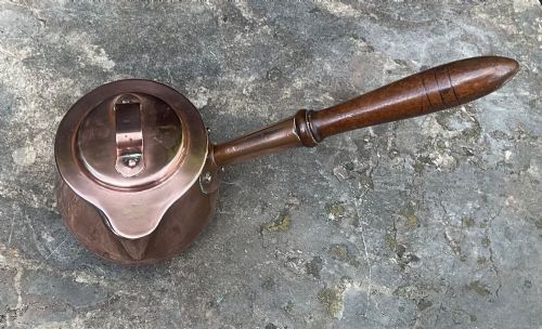 fig 1. An 1830s Georgian copper brandy warmer featuring a polished copper vessel, fitted lid with loop handle, pouring spout, and an extended turned wooden handle.