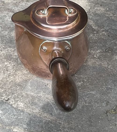 fig 2. An 1830s Georgian copper brandy warmer featuring a polished copper vessel, fitted lid with loop handle, pouring spout, and an extended turned wooden handle.