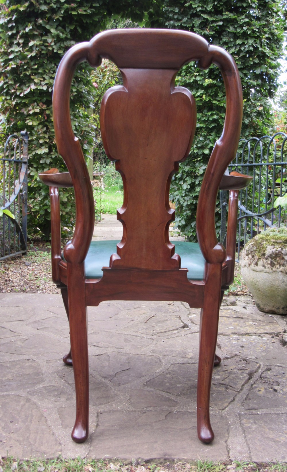 A Georgian style dark mahogany open armchair featuring a vase-shaped back splat, curved arms, a green leather seat, and carved cabriole front legs. View III