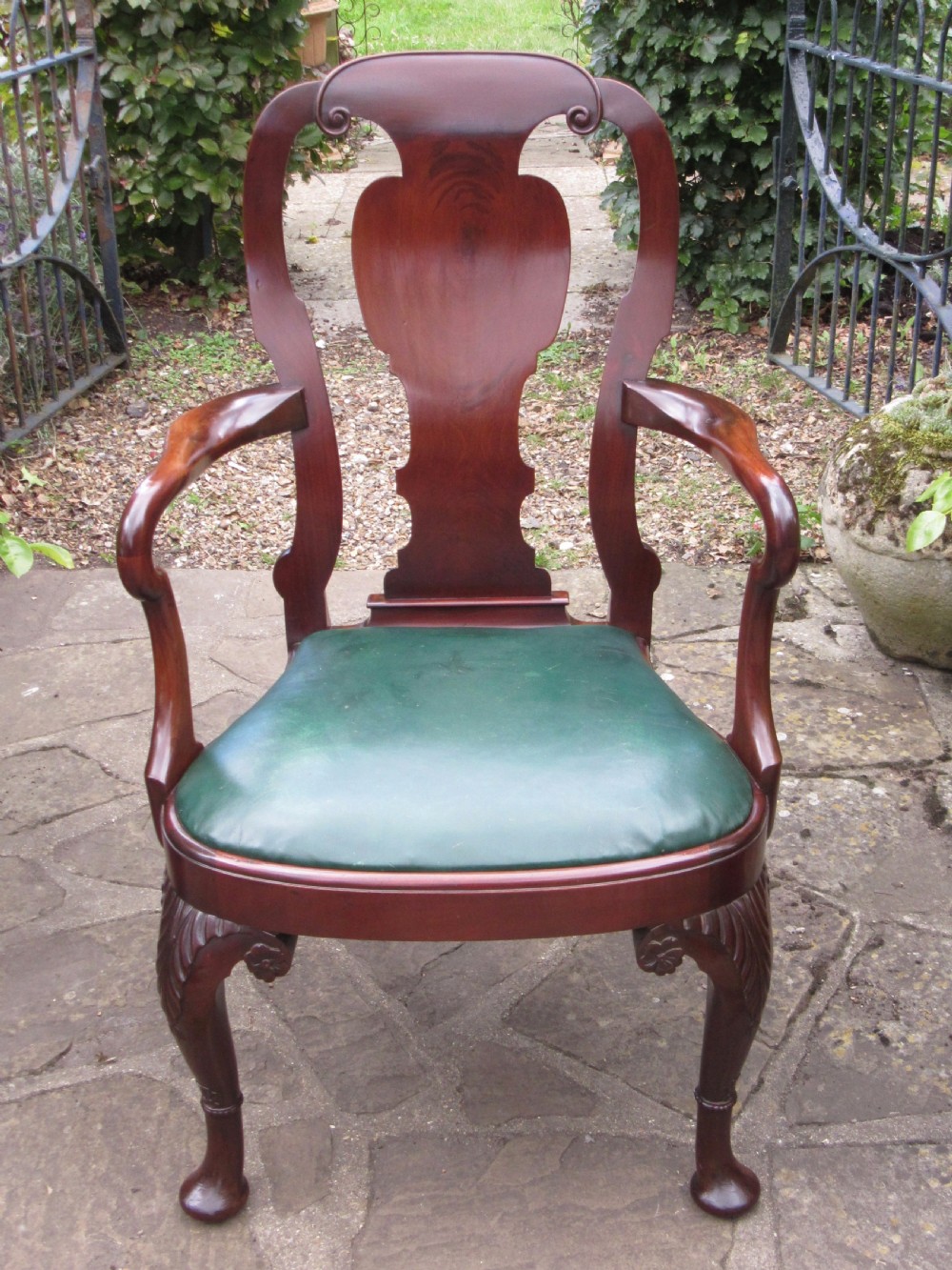 A Georgian style dark mahogany open armchair featuring a vase-shaped back splat, curved arms, a green leather seat, and carved cabriole front legs. View VII