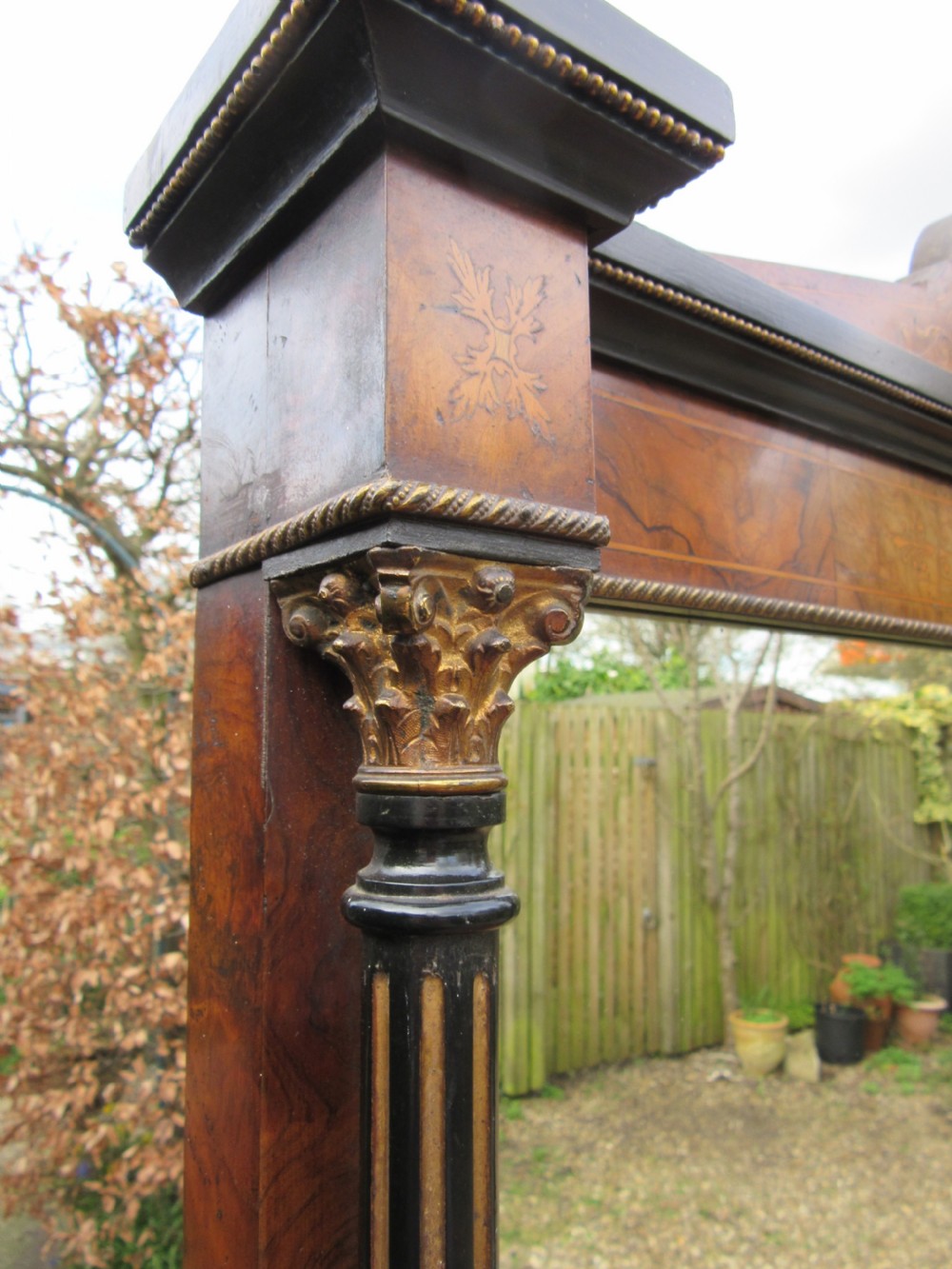 A Victorian walnut display cabinet with a single glazed door, side glass panels, floral marquetry, ebonised columns, and an upper mirror frame topped with finials. View VII