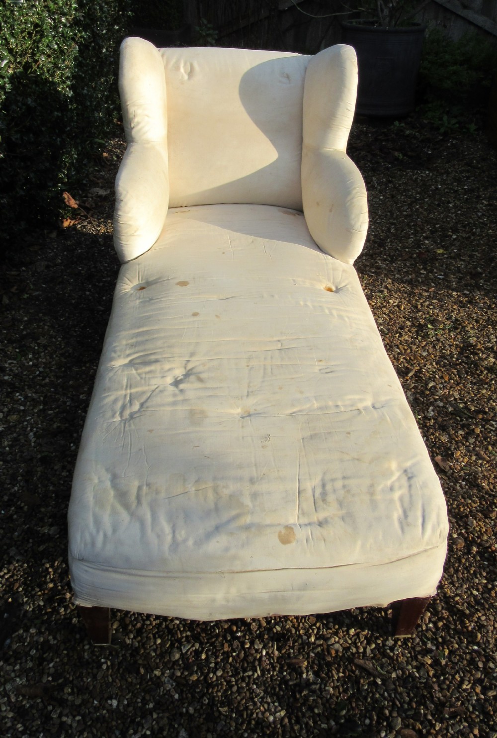 An antique cream calico upholstered day bed featuring a high wingback headrest, tapered mahogany legs, and brass castors. View II