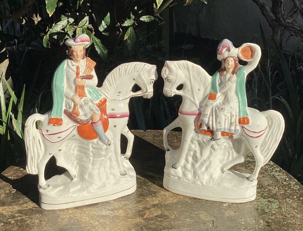 A pair of Victorian Staffordshire white earthenware equestrian figures depicting male and female musicians seated on horses with hand-painted green, orange, and gilt accents.