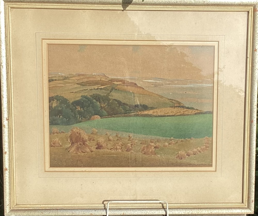 A framed 1943 watercolour painting by Clarence Woodburn depicting rolling green and ochre hills overlooking Cardigan Bay.