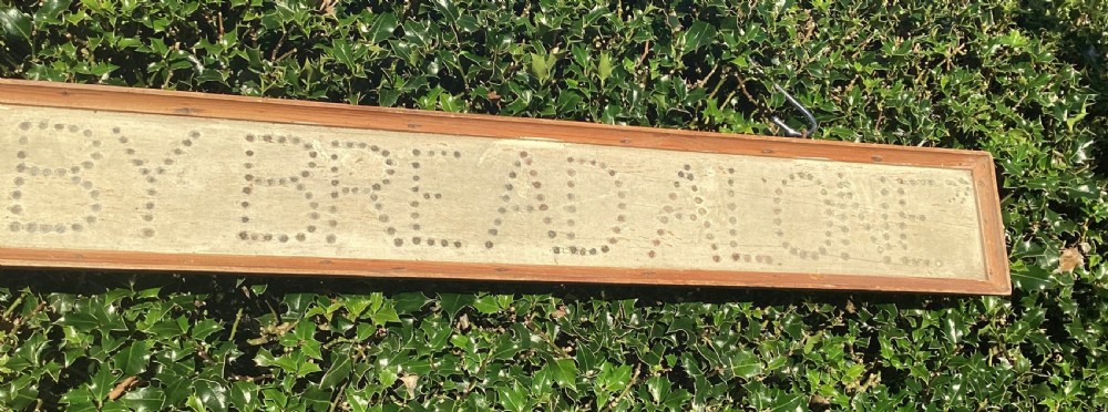 A long horizontal painted pine sign with metal stud lettering spelling out MAN SHALL NOT LIVE BY BREAD ALONE. View II