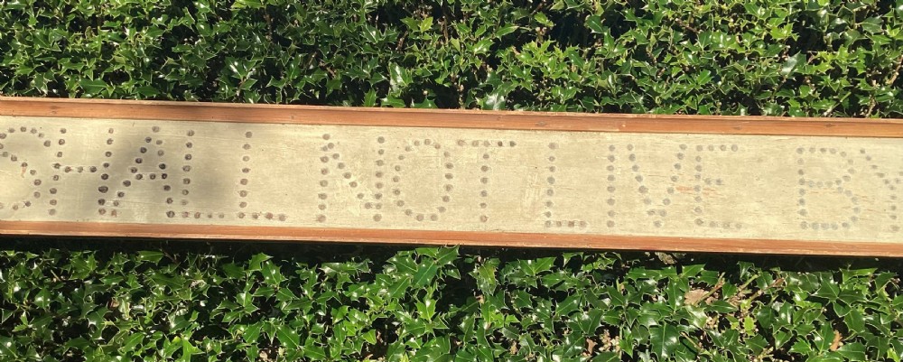 A long horizontal painted pine sign with metal stud lettering spelling out MAN SHALL NOT LIVE BY BREAD ALONE. View III