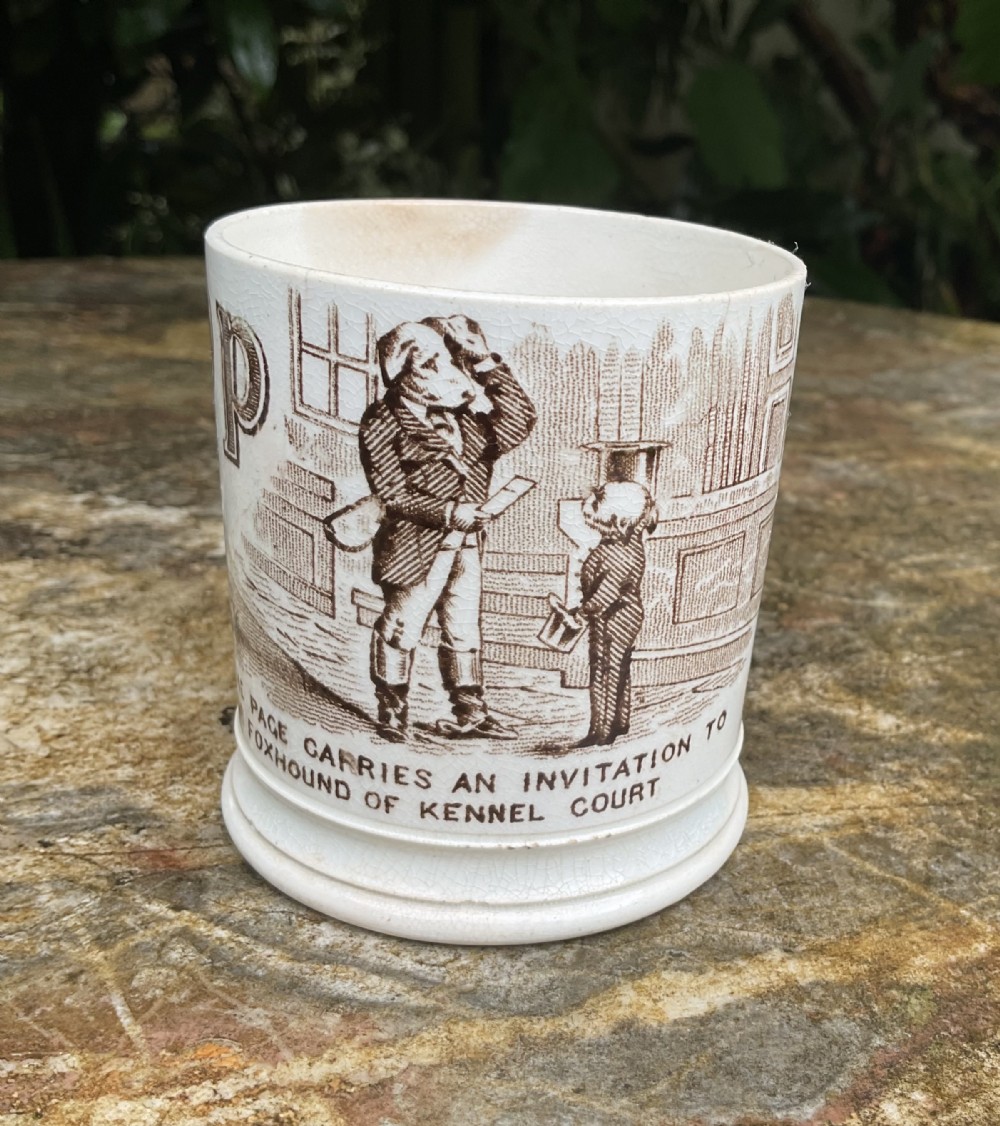 A cylindrical Victorian cream earthenware childs nursery mug featuring a brown transferware print of anthropomorphic dogs.