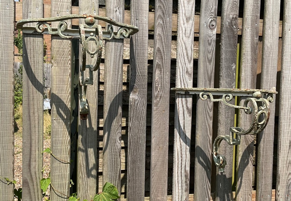 A pair of early 20th-century wrought iron shelf brackets featuring weathered pale green paint and decorative scrollwork. View VI