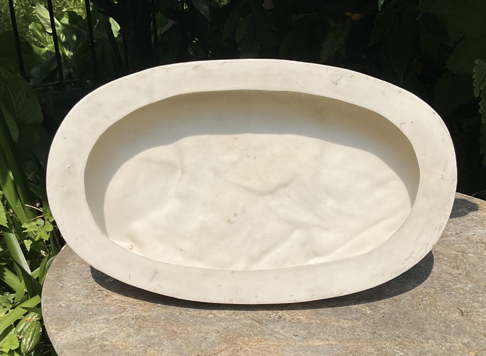 An off-white Victorian Parian porcelain statuette of a reclining soldier leaning against a tree stump on an oval relief-moulded base. View VII