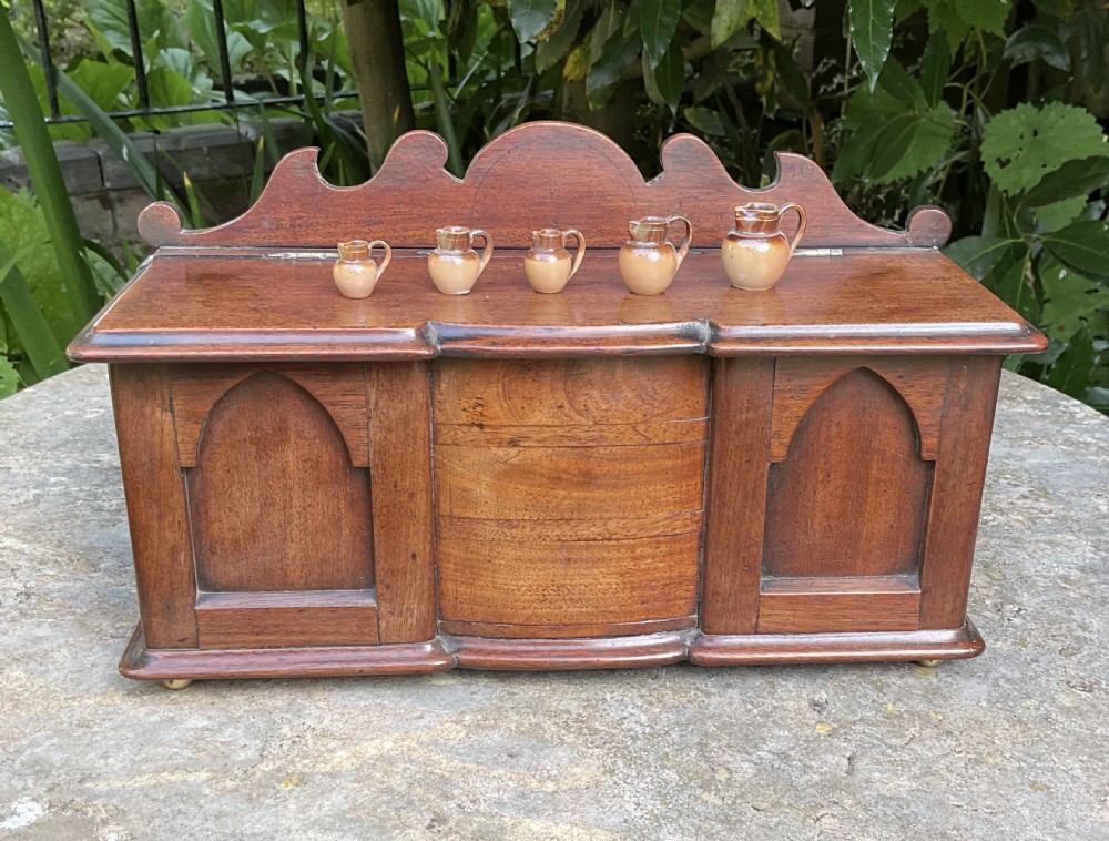 A Victorian mahogany miniature apprentice sideboard featuring a shaped gallery back, breakfront section, and arched panel doors.