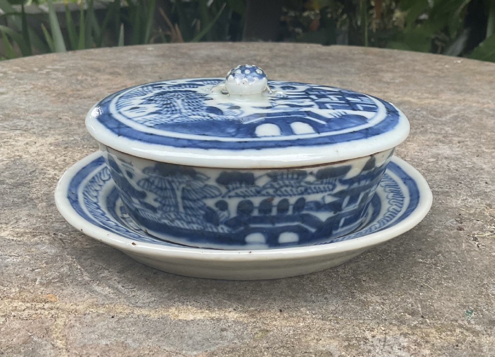 An early nineteenth-century oval Chinese porcelain covered dish on a matching stand decorated with blue and white hand-painted landscape motifs.