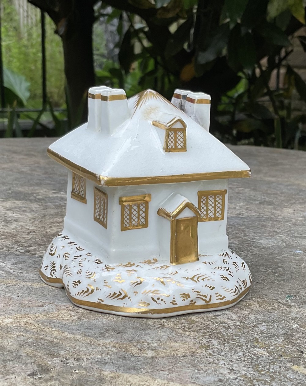 A Regency period white porcelain pastille burner shaped as a cottage featuring gilded chimneys, dormer window, and lattice pattern windows.