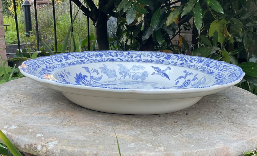 A large Victorian blue and white stone china charger featuring a Chinoiserie landscape scene with figures and an intricate floral border. View V
