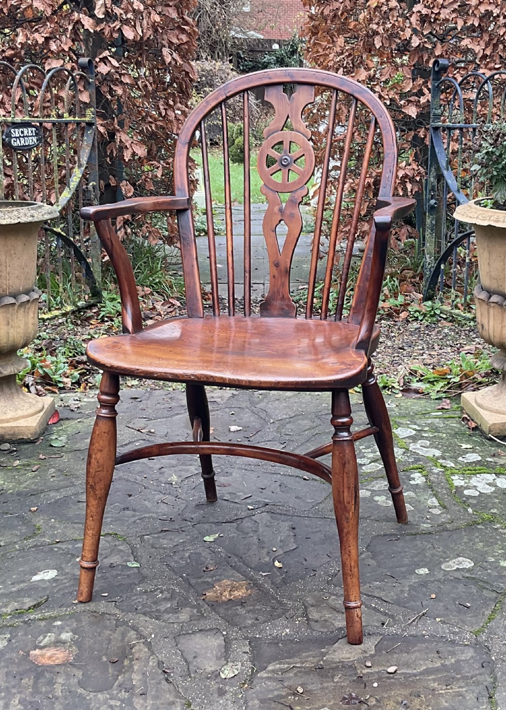 A Georgian yew and elm wheel back Windsor armchair with a hooped back, shaped saddle seat, swept arms, and turned legs joined by a curved stretcher.