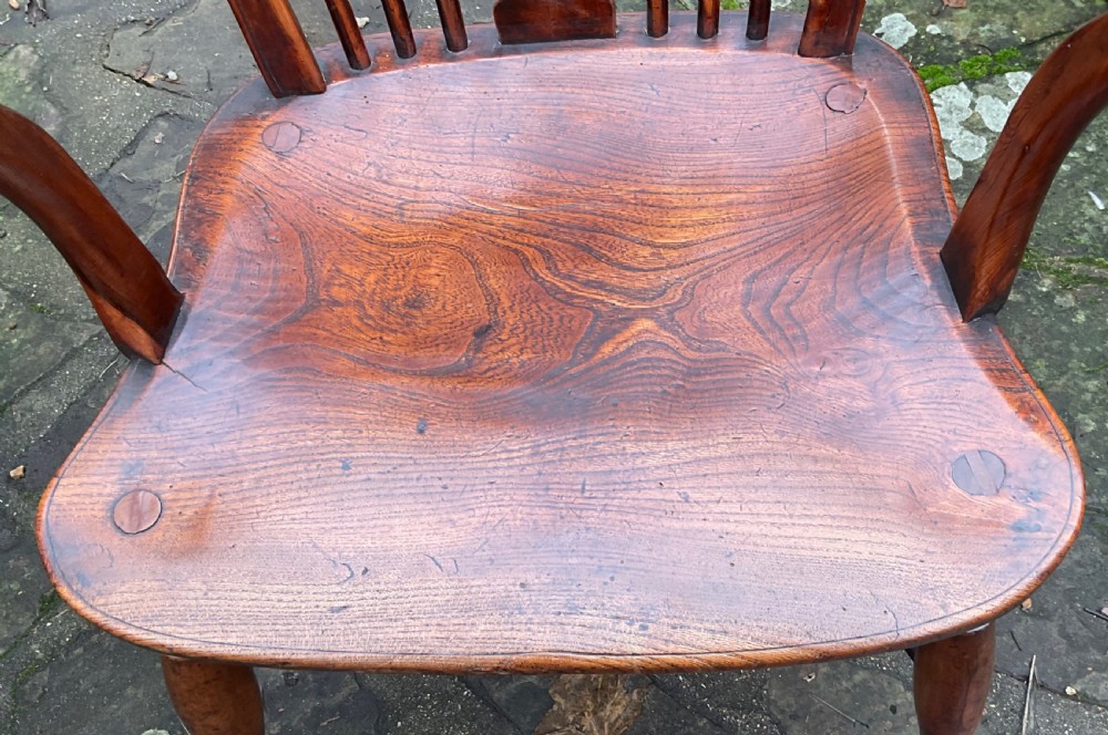 A Georgian yew and elm wheel back Windsor armchair with a hooped back, shaped saddle seat, swept arms, and turned legs joined by a curved stretcher. View II