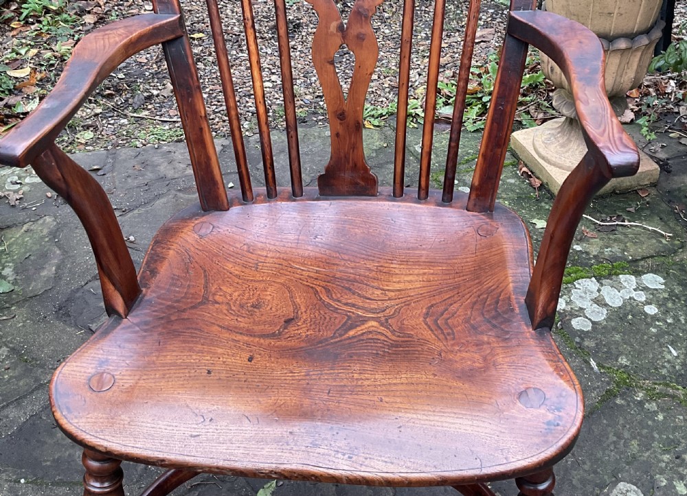 A Georgian yew and elm wheel back Windsor armchair with a hooped back, shaped saddle seat, swept arms, and turned legs joined by a curved stretcher. View III