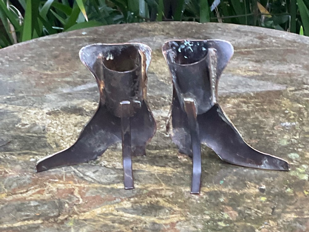 A pair of polished copper boot ornaments featuring scalloped brass button trims and brass toe caps facing each other. View II