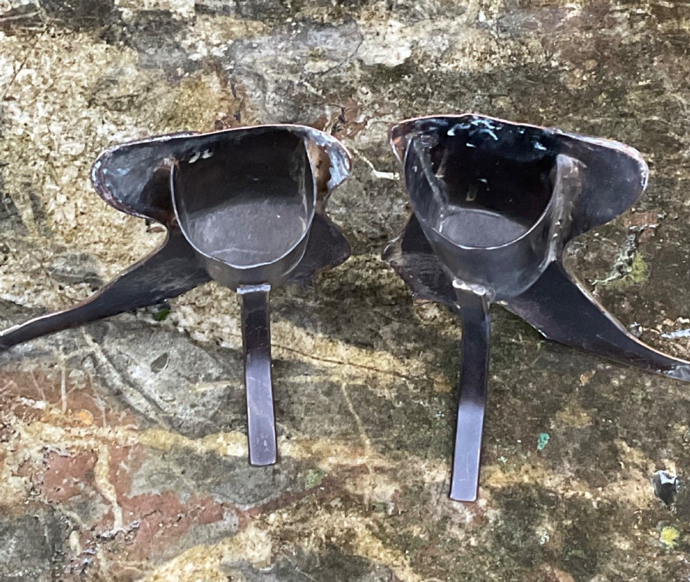 A pair of polished copper boot ornaments featuring scalloped brass button trims and brass toe caps facing each other. View III
