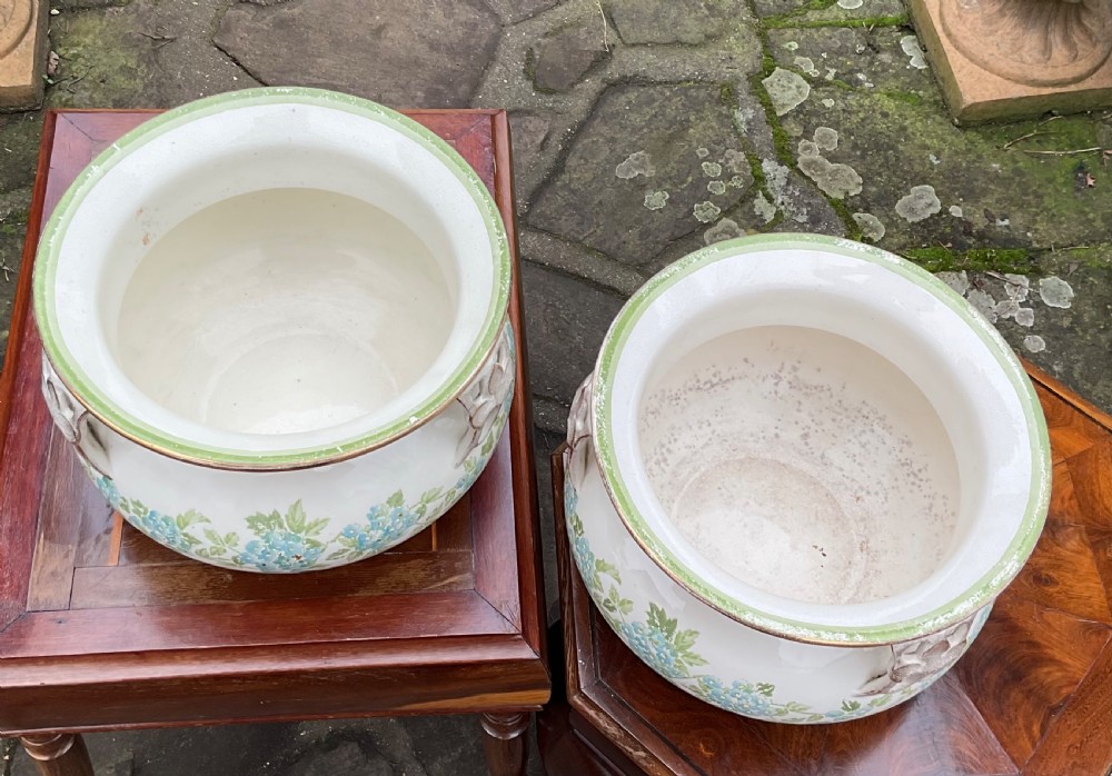 A pair of cream English pottery jardinieres featuring blue floral garlands, gilded rims, and three reticulated handles. View III