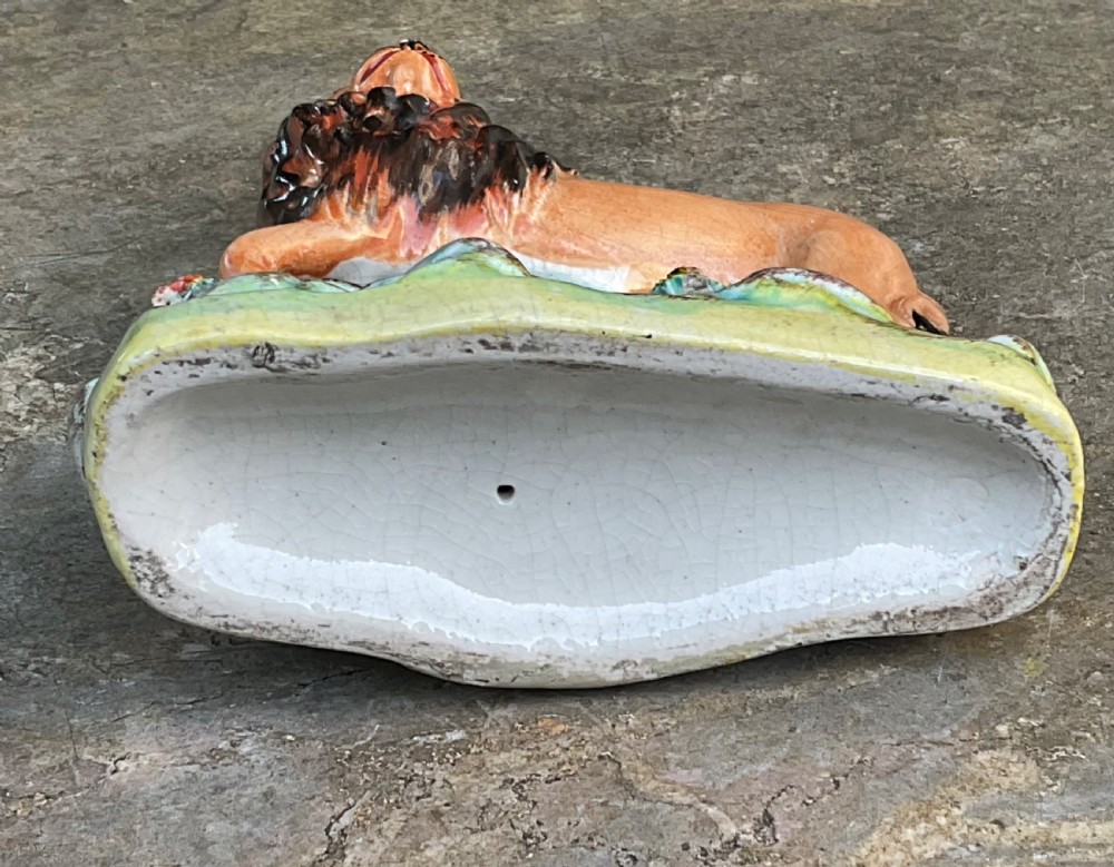 A Victorian Staffordshire earthenware figurine depicting a tawny brown lion standing on a rocky turquoise base. View V