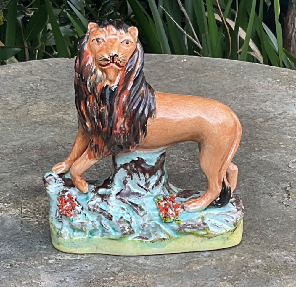 A Victorian Staffordshire earthenware figurine depicting a tawny brown lion standing on a rocky turquoise base. View VIII