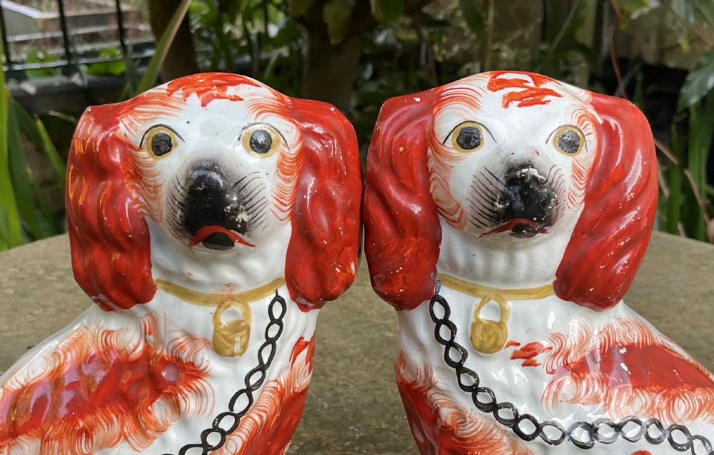 A pair of Victorian earthenware Staffordshire spaniel figurines painted with red patches, black snouts, and gilt chains. View V