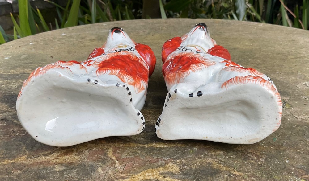 A pair of Victorian earthenware Staffordshire spaniel figurines painted with red patches, black snouts, and gilt chains. View VI