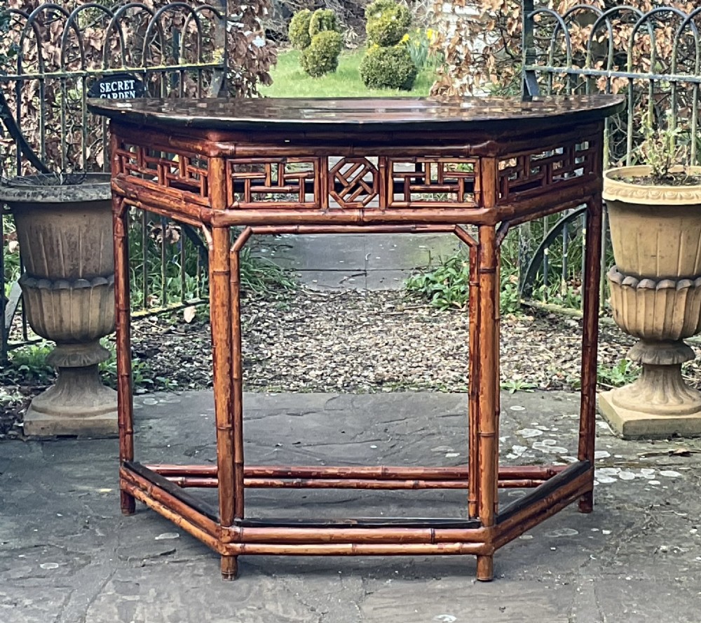 An antique dark bamboo demilune console table featuring a semicircular top and decorative geometric fretwork along the apron.