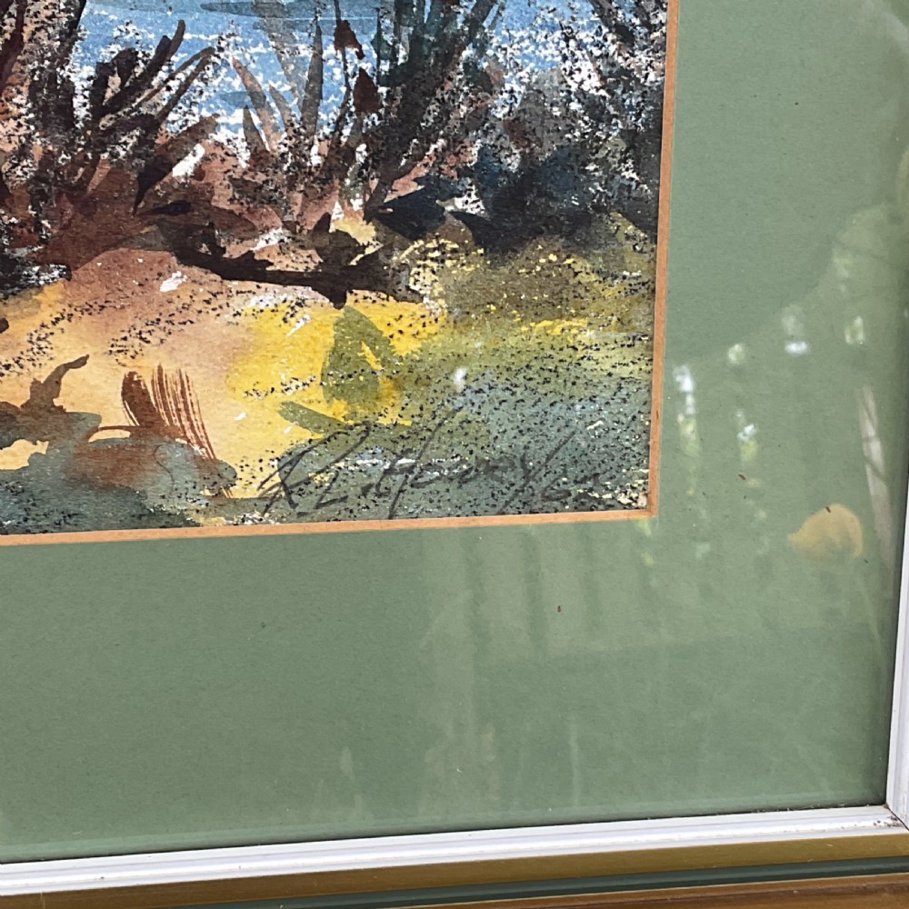 A framed watercolour landscape painting depicting a mountain lake framed by trees under a cloudy sky, mounted in green and framed in gold. View III