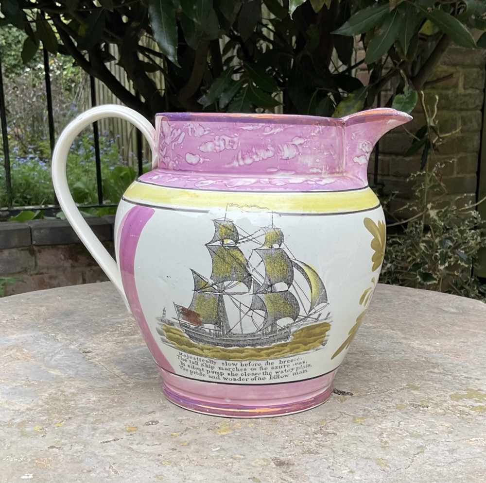 A Georgian Sunderland pink splash lustre pottery jug decorated with a transfer-printed tall ship, verse inscription, and yellow accents.
