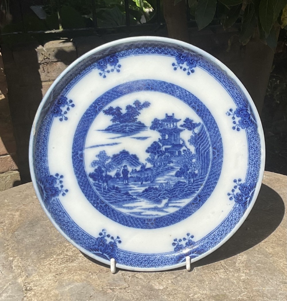 A circular Georgian blue and white ceramic bread stand featuring a detailed Chinoiserie buffalo pattern.