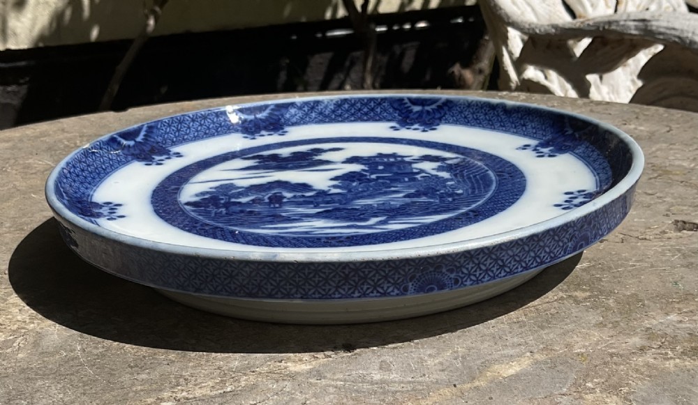 A circular Georgian blue and white ceramic bread stand featuring a detailed Chinoiserie buffalo pattern. View VI